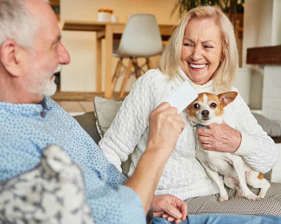 resident couple laughing while holding their dog