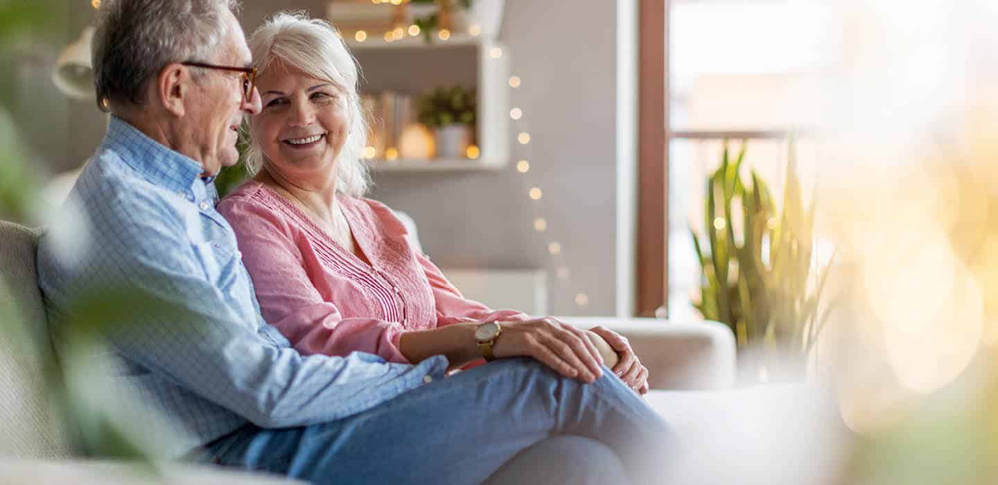 resident couple sitting on the couch smiling and holding each other