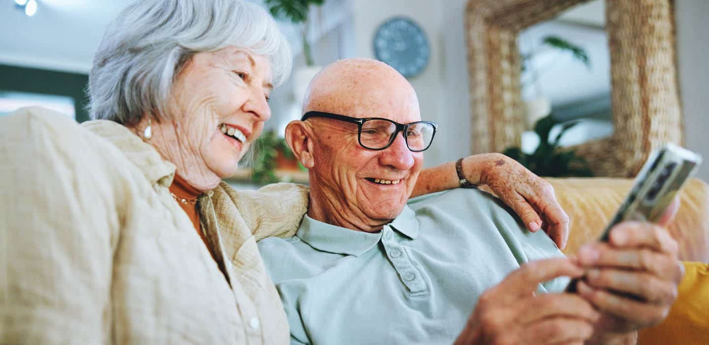 older couple laughing at something on their phone